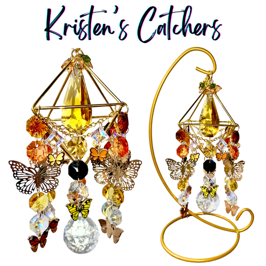 Handcrafted gold 3D geometric tabletop sun catcher with 20 butterfly charms, amber center crystal, warm-toned crystal fringe, and large clear ball pendant. Includes gold display stand.