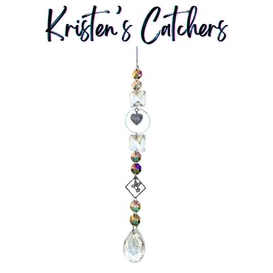 Handcrafted Mother's Day sun catcher with silver hummingbird charm, filigree heart, oil-slick iridescent beads, square crystal connectors, and a clear teardrop pendant drop.