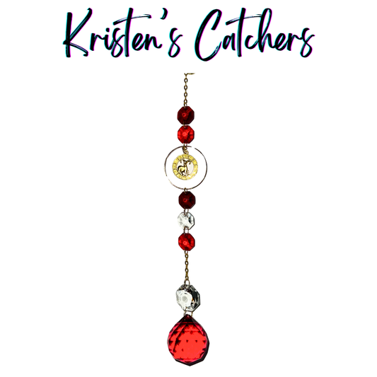 Gold Aries sun catcher with red crystal accents and clear prisms creating dancing light patterns