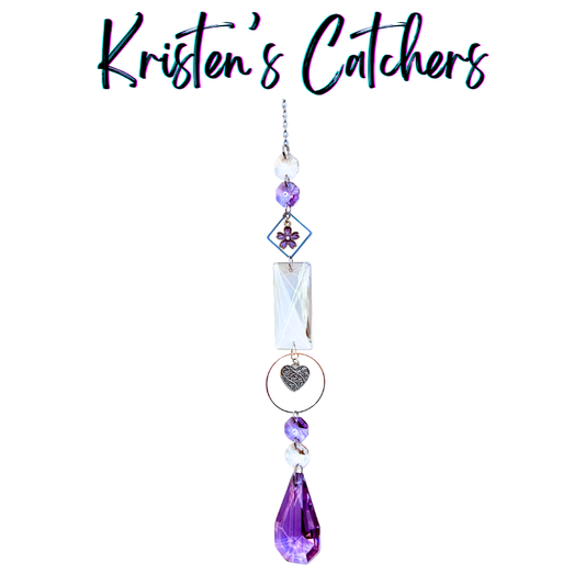 Handcrafted Mother's Day sun catcher with purple flower charm, silver filigree heart, rectangular prism connector, violet beads, and a deep amethyst teardrop pendant drop.