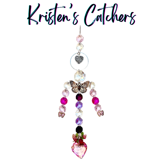 Handcrafted Mother's Day sun catcher with silver filigree butterfly, mom heart charm, pink flower accents, cascading pink and lavender crystals, and a rose-crowned pink heart pendant.