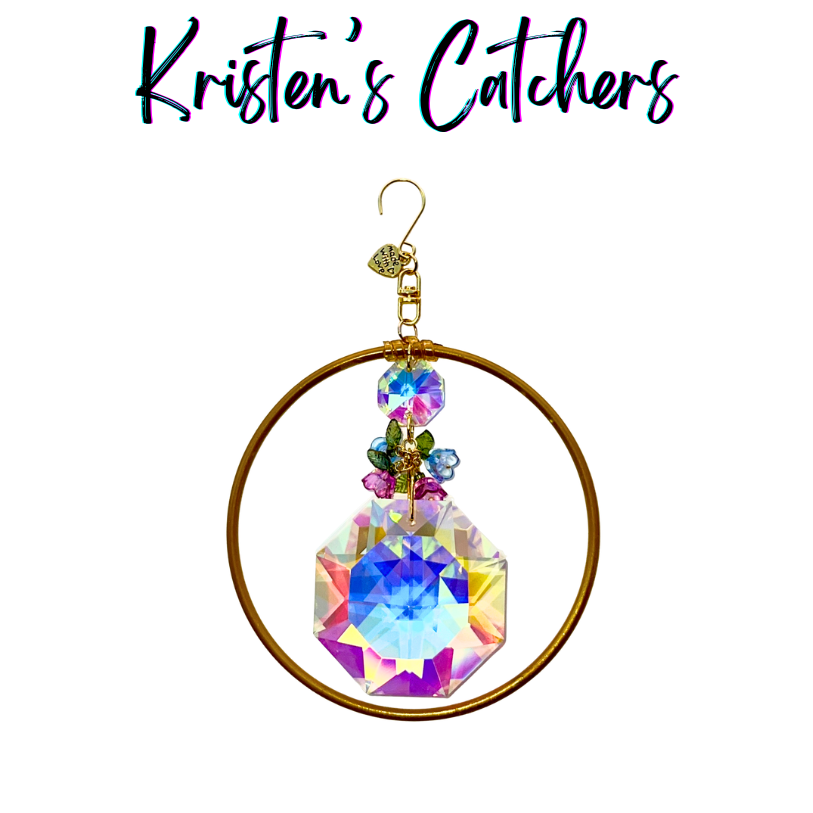 Handcrafted 4-inch ornamental sun catcher with large A/B iridescent octagon crystal, bronze ring frame, and enamel flower charm cluster in pink blue and green.