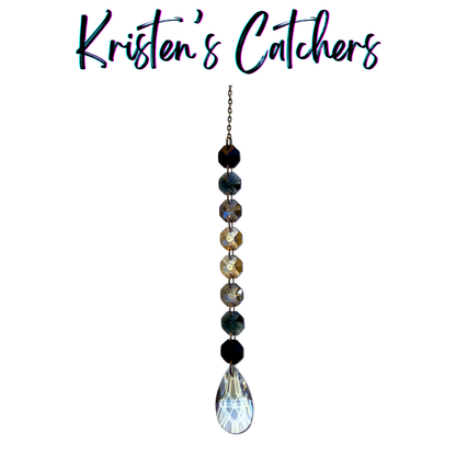 Handcrafted single strand black gradient sun catcher with bronze hardware flowing from deep black through champagne gold to a clear iridescent teardrop pendant drop.